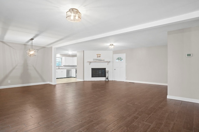 unfurnished living room with dark hardwood / wood-style flooring, beam ceiling, and a fireplace