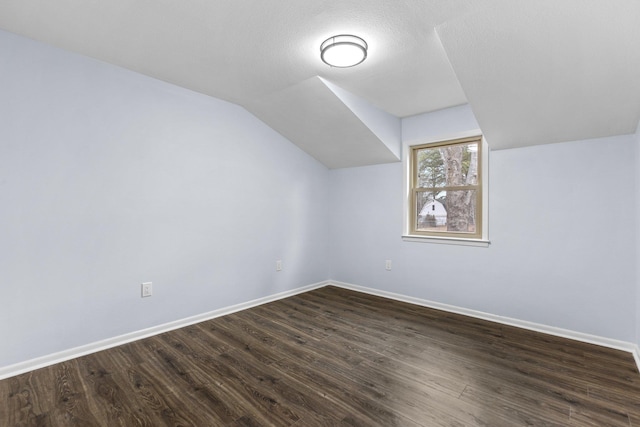 bonus room with lofted ceiling, dark hardwood / wood-style floors, and a textured ceiling