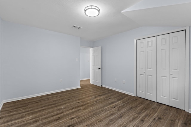 unfurnished bedroom featuring dark wood-type flooring, vaulted ceiling, and a closet