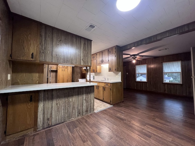 kitchen featuring wooden walls, sink, dark hardwood / wood-style flooring, ceiling fan, and kitchen peninsula