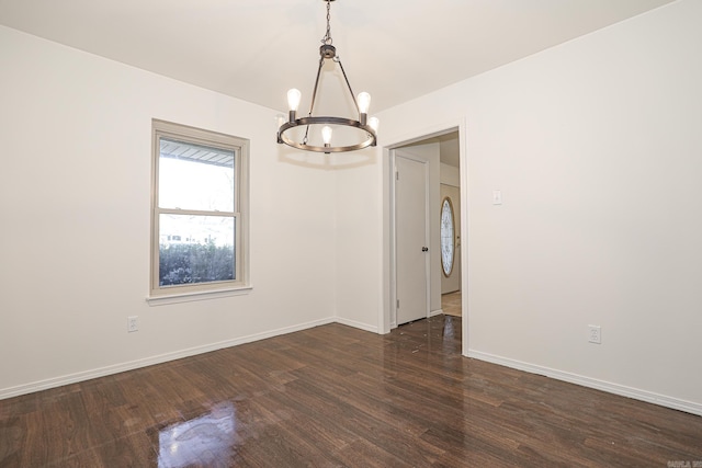 unfurnished room featuring a notable chandelier and dark wood-type flooring