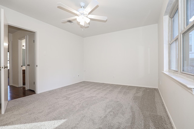 spare room with ceiling fan and dark carpet