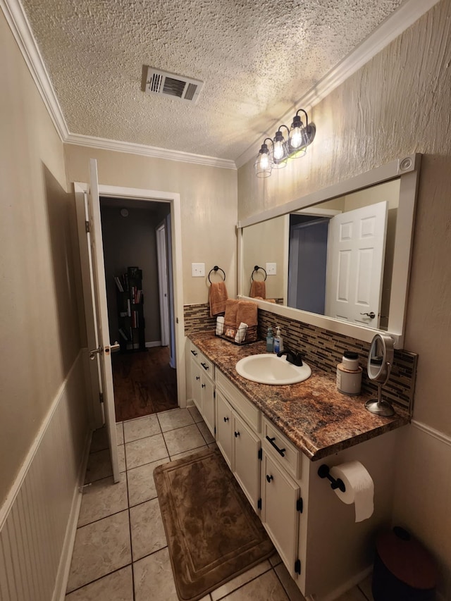 bathroom featuring backsplash, vanity, crown molding, tile patterned floors, and a textured ceiling