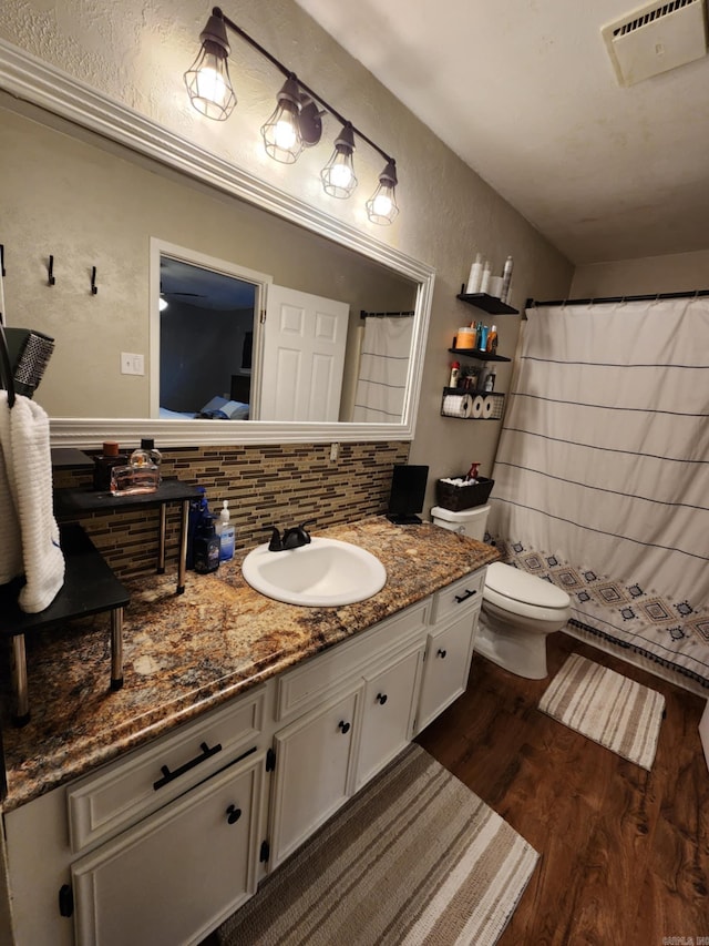 bathroom featuring hardwood / wood-style flooring, vanity, toilet, and decorative backsplash