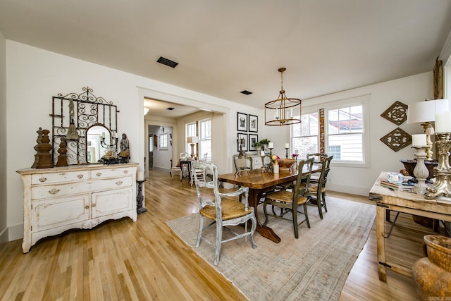 dining space featuring an inviting chandelier, a healthy amount of sunlight, and light wood-type flooring