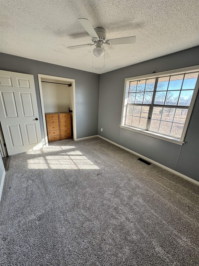 unfurnished bedroom with a closet, ceiling fan, carpet floors, and a textured ceiling