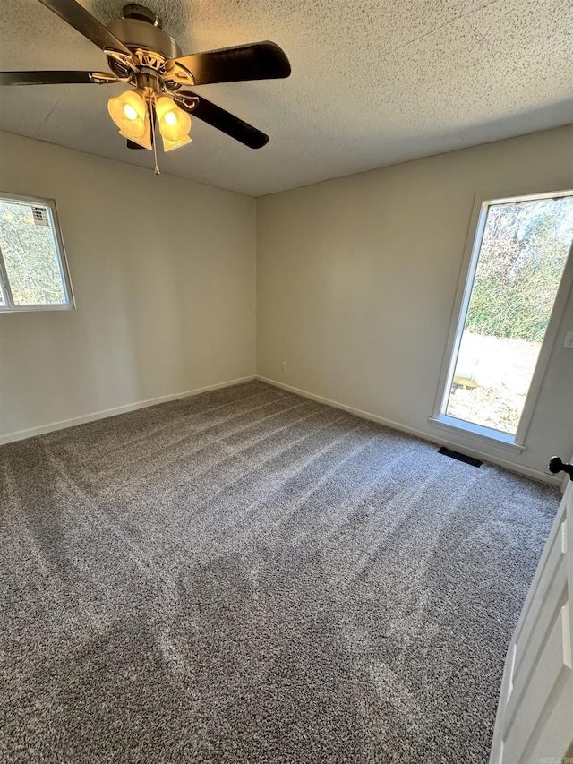 carpeted spare room featuring ceiling fan and a textured ceiling