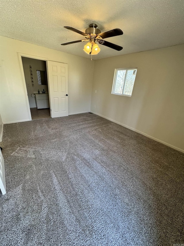 unfurnished bedroom with dark colored carpet, ceiling fan, a textured ceiling, and ensuite bath