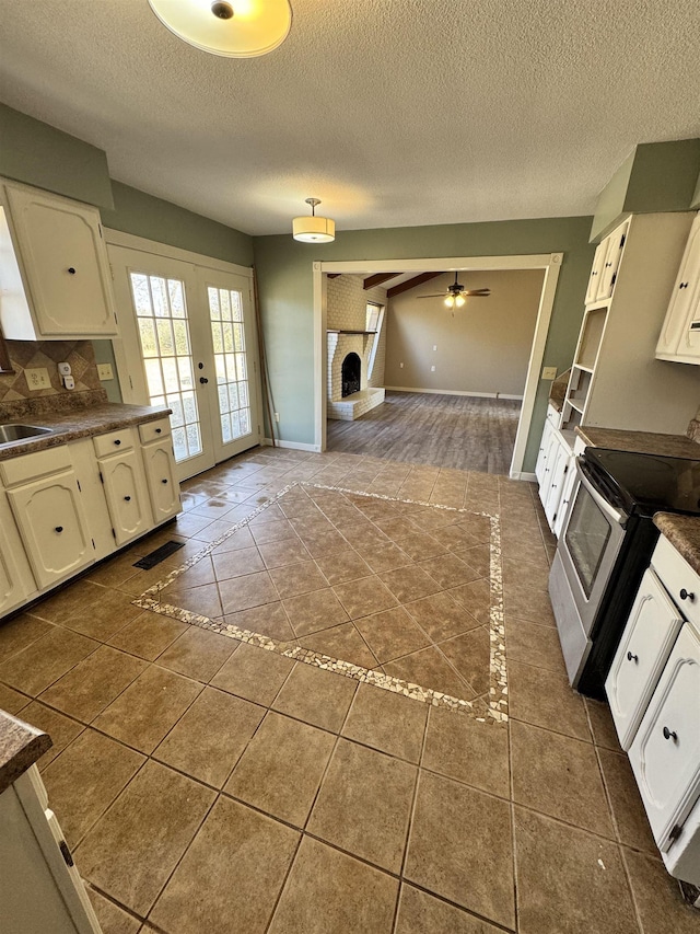 kitchen with electric stove, sink, a fireplace, and dark tile patterned floors