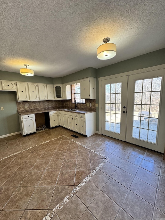 kitchen featuring french doors, sink, white cabinetry, tile patterned flooring, and decorative backsplash