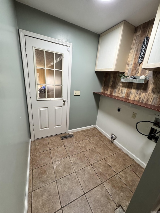 clothes washing area with electric dryer hookup, light tile patterned floors, washer hookup, and cabinets