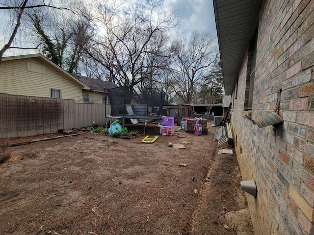 view of yard featuring a trampoline and central AC