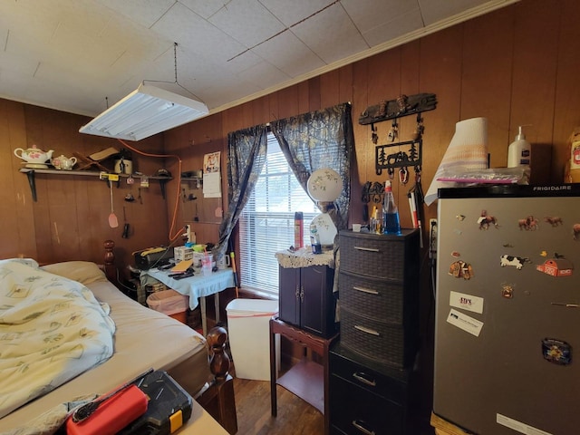 bedroom featuring stainless steel fridge, wooden walls, and wood-type flooring