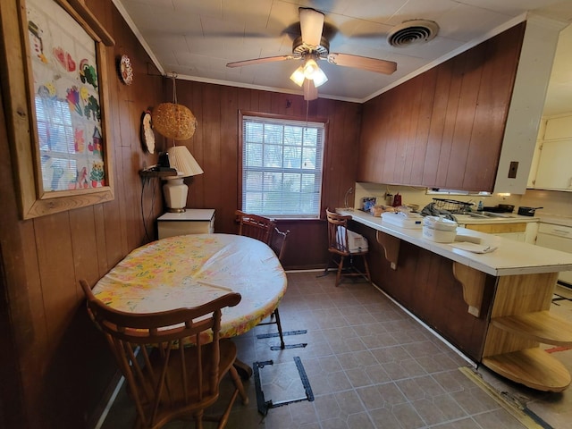 home office with ceiling fan, ornamental molding, and wooden walls