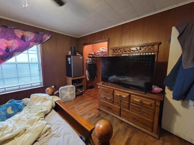 bedroom featuring crown molding, hardwood / wood-style flooring, a walk in closet, a closet, and wood walls