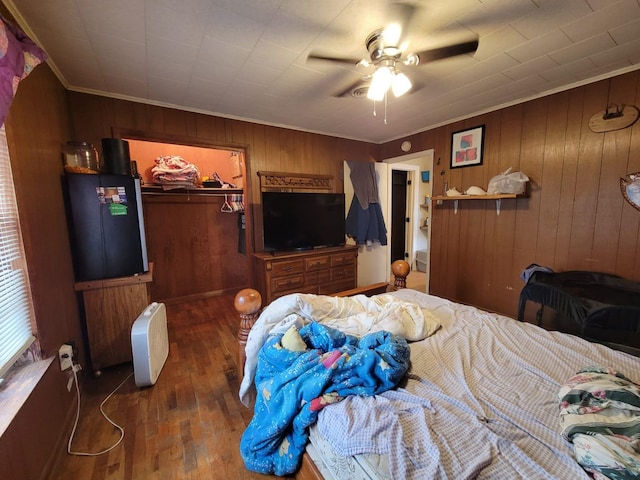 bedroom featuring wood walls, a walk in closet, dark hardwood / wood-style floors, a closet, and ceiling fan