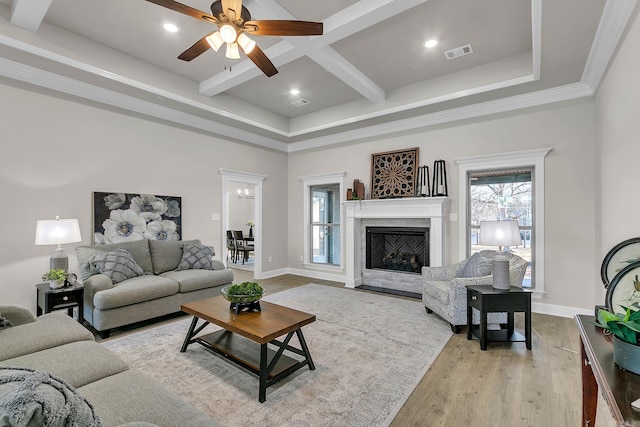 living room with beam ceiling, a healthy amount of sunlight, coffered ceiling, and light wood-type flooring