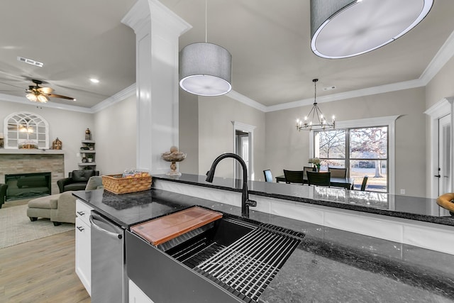 kitchen featuring pendant lighting, ornamental molding, dark stone counters, and sink