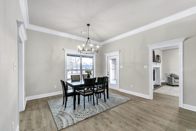 dining room with an inviting chandelier, wood-type flooring, and ornamental molding