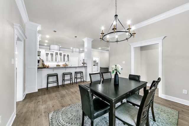 dining space featuring hardwood / wood-style flooring, crown molding, sink, and a chandelier