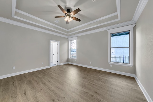 unfurnished room with crown molding, ceiling fan, a tray ceiling, and light hardwood / wood-style flooring