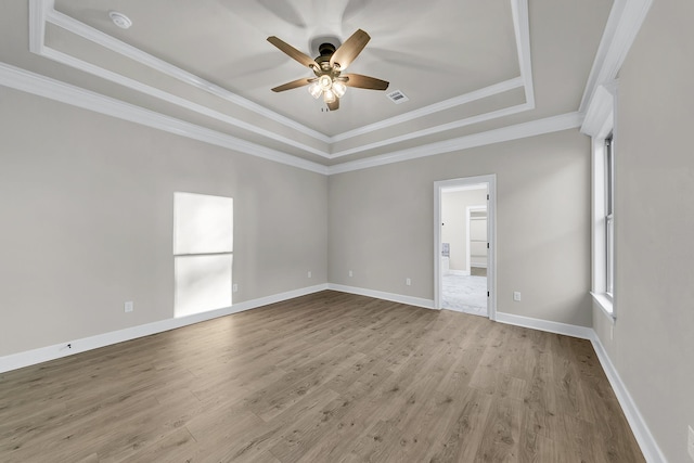 unfurnished room featuring a raised ceiling, crown molding, ceiling fan, and light hardwood / wood-style flooring