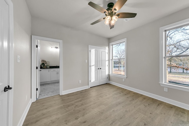 unfurnished bedroom featuring ceiling fan, ensuite bath, and light hardwood / wood-style flooring