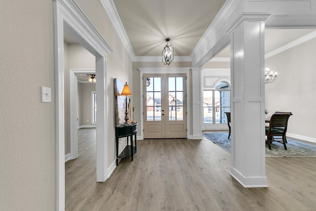 foyer featuring an inviting chandelier, ornamental molding, french doors, and light hardwood / wood-style flooring