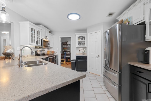 kitchen featuring light tile patterned flooring, white cabinetry, sink, hanging light fixtures, and stainless steel appliances