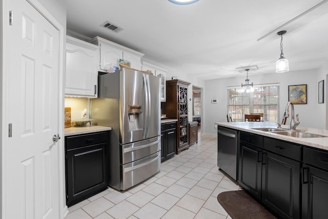 kitchen with light tile patterned flooring, sink, white cabinetry, appliances with stainless steel finishes, and pendant lighting