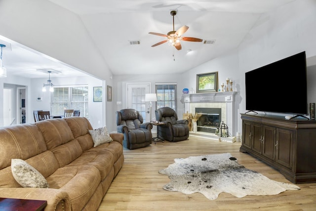 living room featuring a tile fireplace, plenty of natural light, ceiling fan, and light hardwood / wood-style flooring