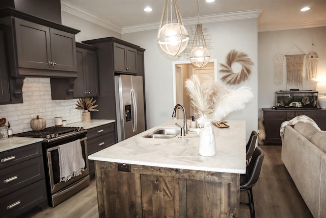 kitchen with a kitchen island with sink, sink, a kitchen breakfast bar, and appliances with stainless steel finishes