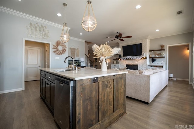 kitchen featuring pendant lighting, dishwasher, sink, a kitchen island with sink, and light wood-type flooring