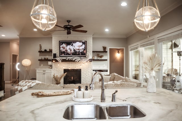 kitchen featuring pendant lighting, sink, light stone countertops, and a brick fireplace