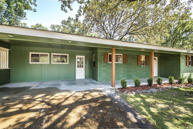 view of front of home featuring a carport, covered porch, brick siding, and driveway