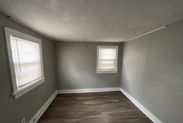 spare room featuring dark hardwood / wood-style floors and a textured ceiling