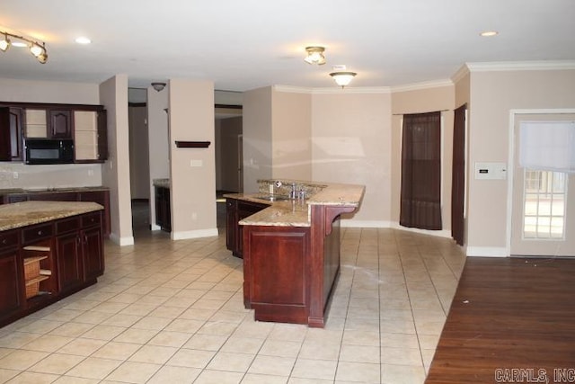 kitchen with sink, a breakfast bar area, a center island, crown molding, and light stone countertops