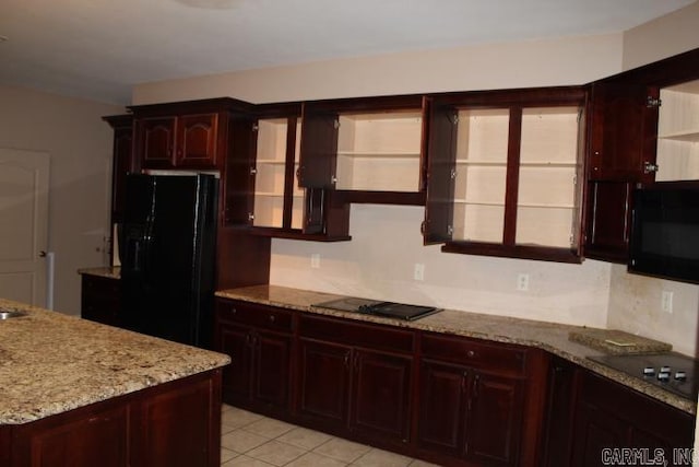 kitchen with light stone countertops, light tile patterned floors, and black appliances