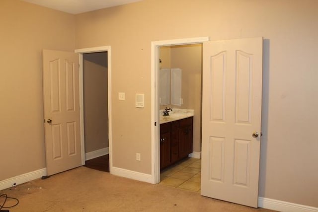 unfurnished bedroom with connected bathroom, sink, and light carpet