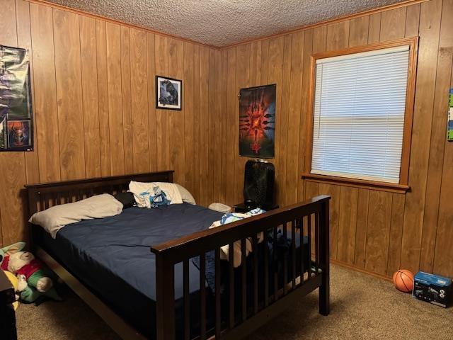 bedroom featuring wood walls, a textured ceiling, and carpet