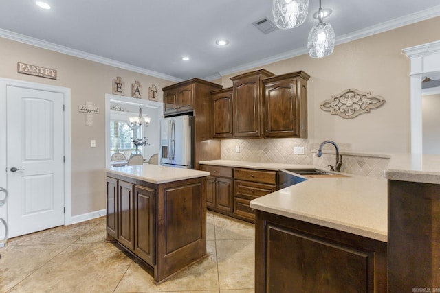 kitchen featuring pendant lighting, sink, dark brown cabinets, a center island, and fridge with ice dispenser