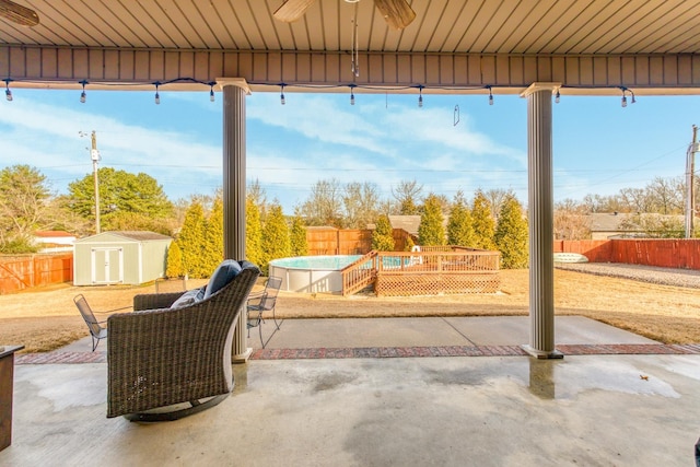 view of patio featuring ceiling fan, a storage shed, and a fenced in pool