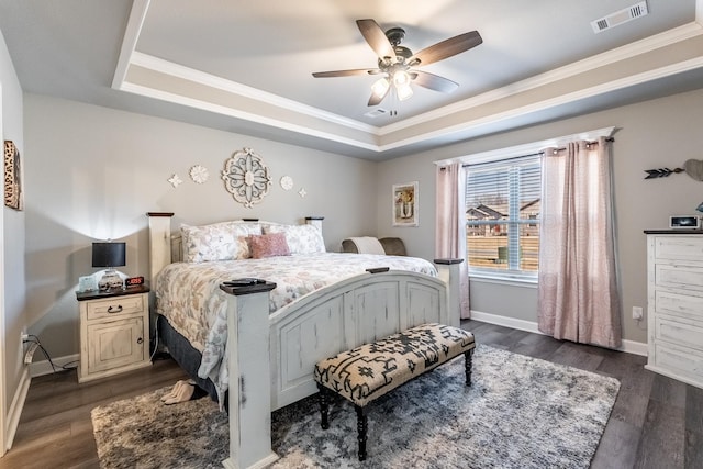 bedroom with crown molding, dark wood-type flooring, and a tray ceiling