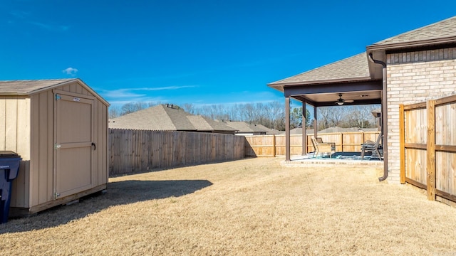 view of yard with ceiling fan and a storage shed