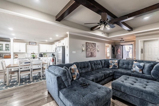 living room featuring ceiling fan, light wood-type flooring, and beam ceiling