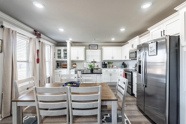 kitchen with dark wood-type flooring, white cabinetry, crown molding, stainless steel appliances, and backsplash