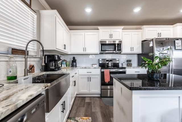 kitchen with sink, appliances with stainless steel finishes, white cabinetry, light stone countertops, and dark hardwood / wood-style flooring