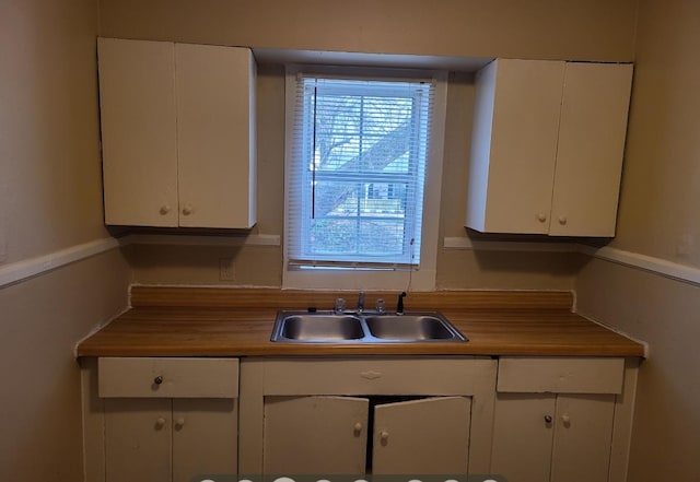 kitchen featuring wood counters, sink, and white cabinets