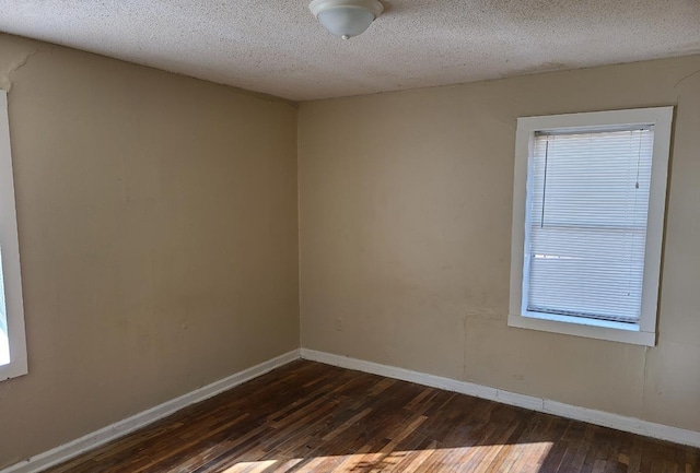 unfurnished room featuring dark wood-type flooring and a textured ceiling