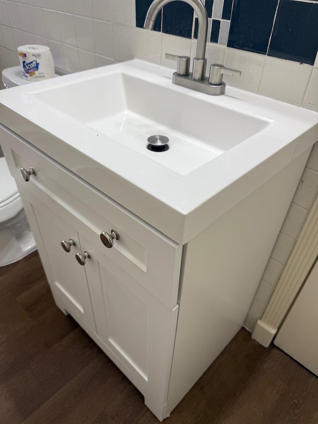 bathroom with vanity, backsplash, wood-type flooring, and toilet